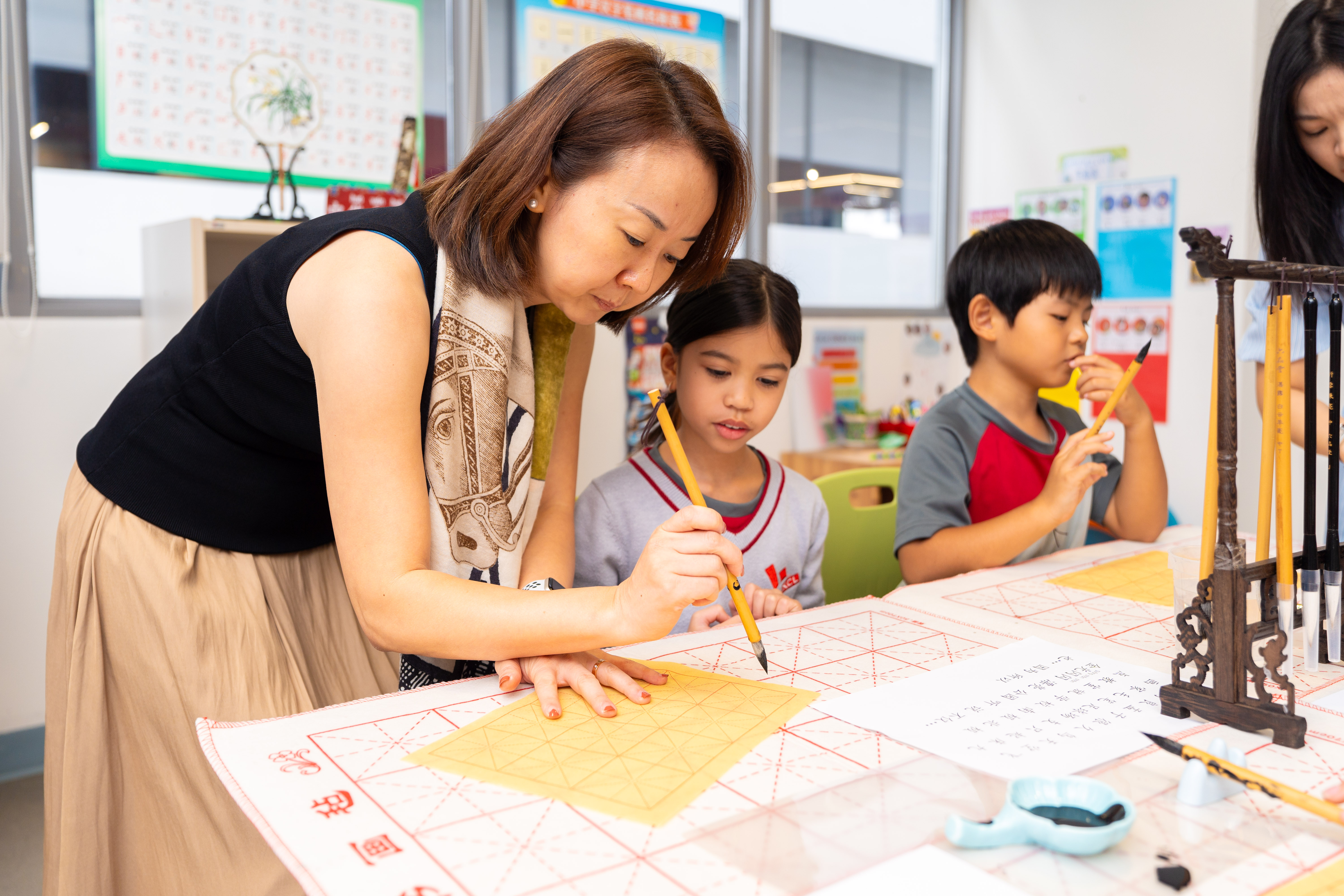 Teacher guiding students in a Chinese calligraphy class at XCL World Academy