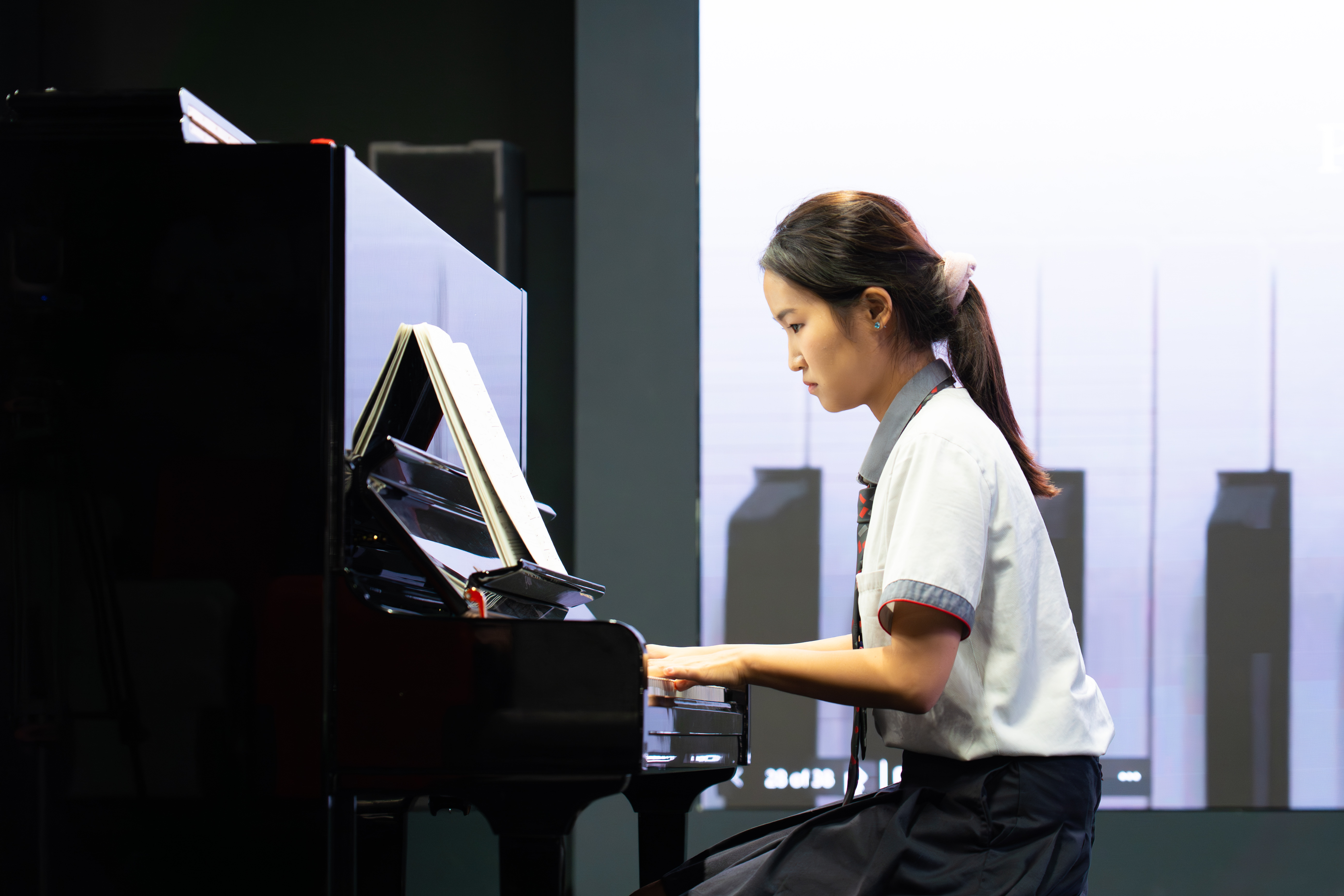A student playing a grand piano on stage