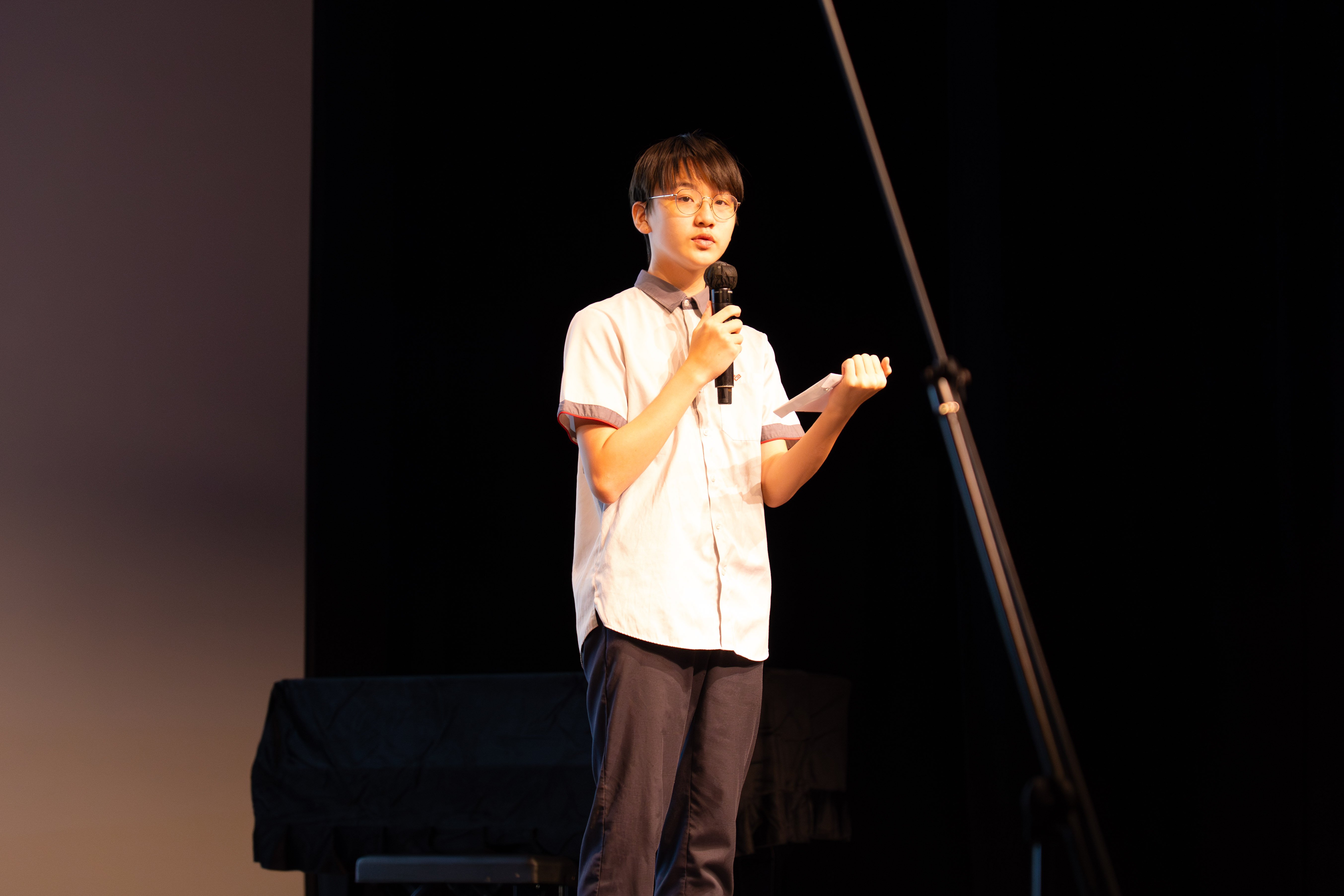 A student speaking on stage with a microphone