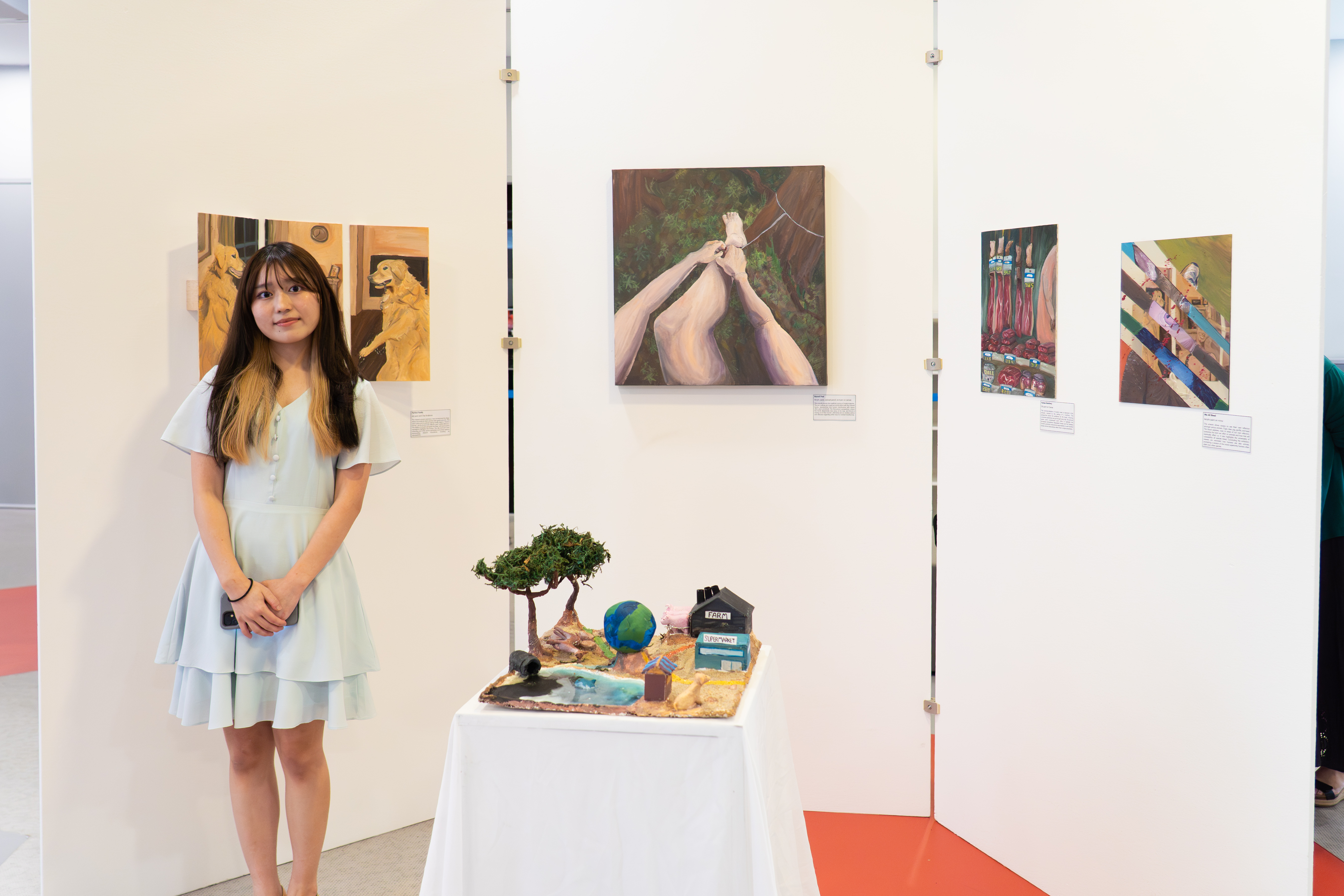A student standing beside her artwork display at the DP Arts Showcase