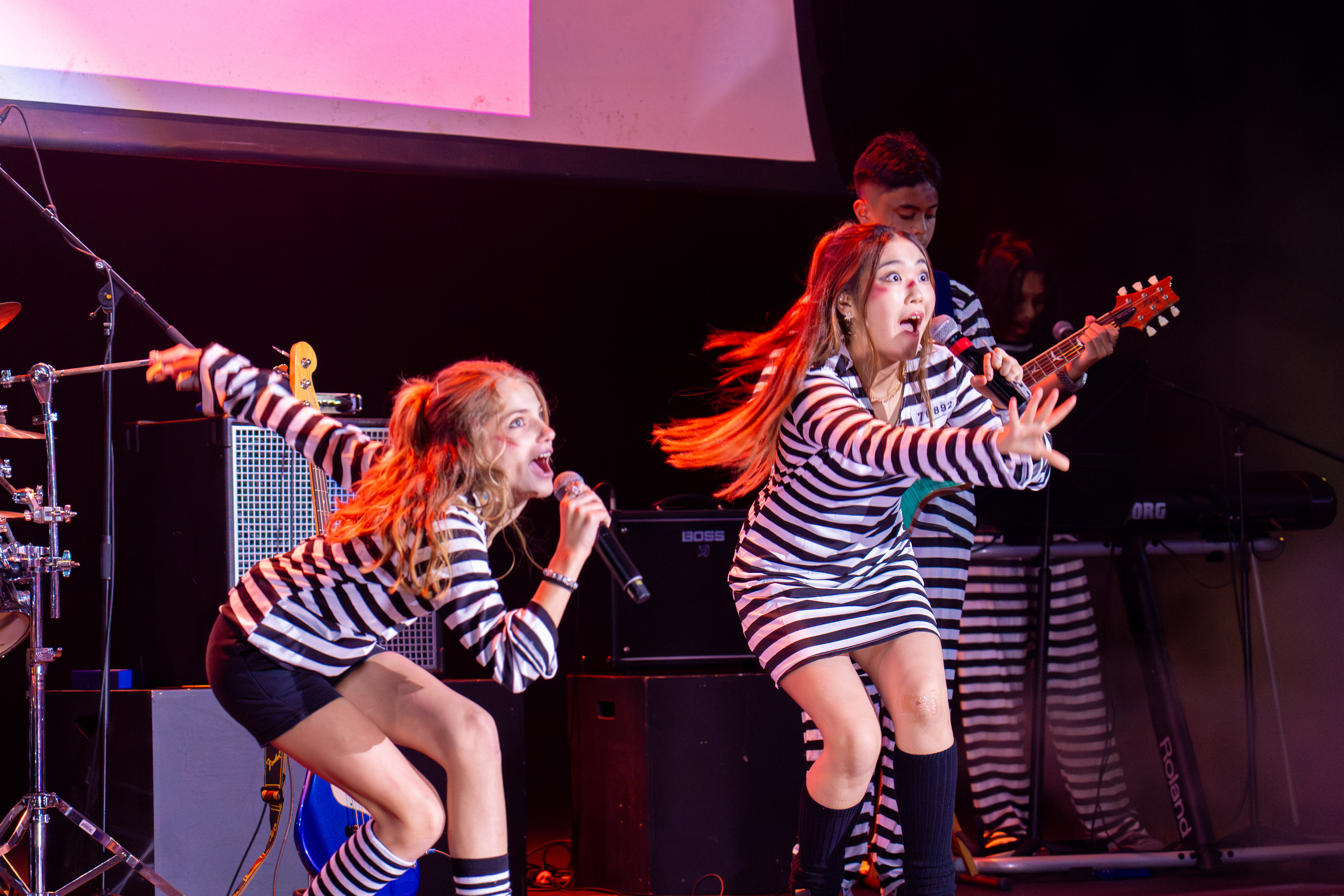 Students singing on stage in striped costumes during Battle of the Bands
