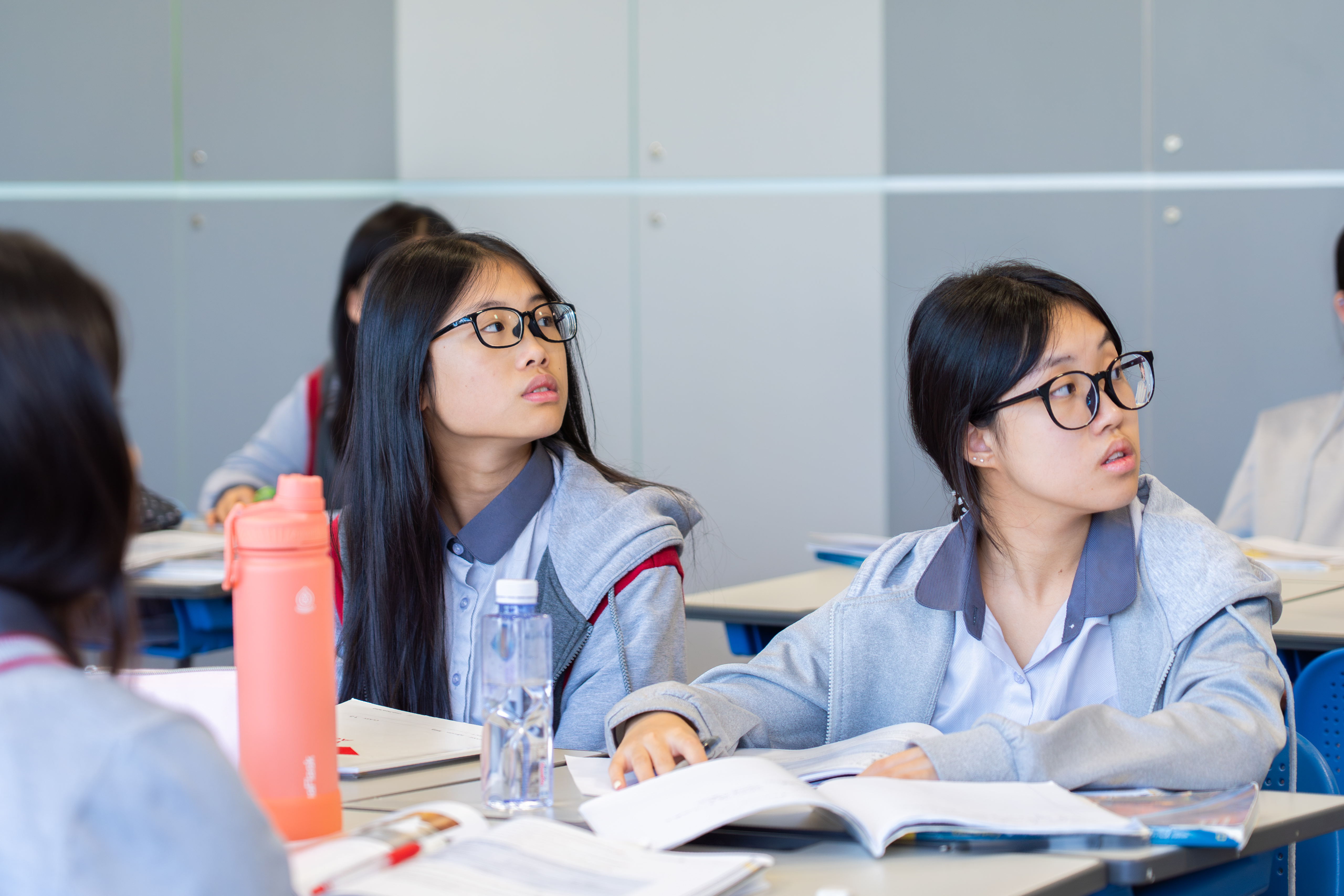Two students taking notes in class