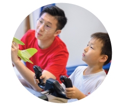 An instructor and a boy with a foam aeroplane at a flight simulator