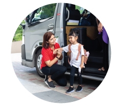A staff member helping a girl with a backpack beside a vehicle