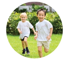 Two young children running on a lawn