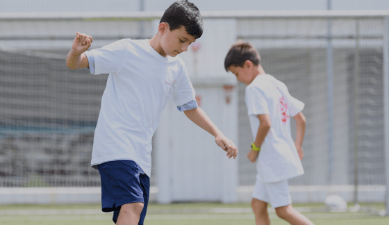 Two boys playing football on a sports field