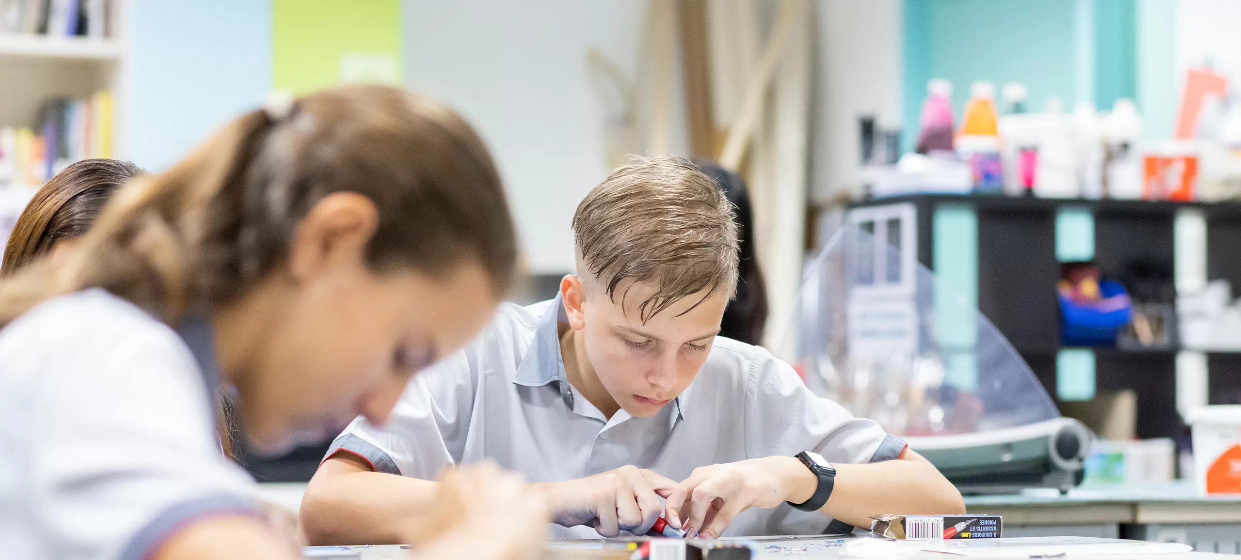 A student working intently on a craft project in the art room