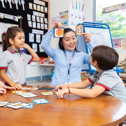 A teacher using flashcards with two young students in a Mandarin class