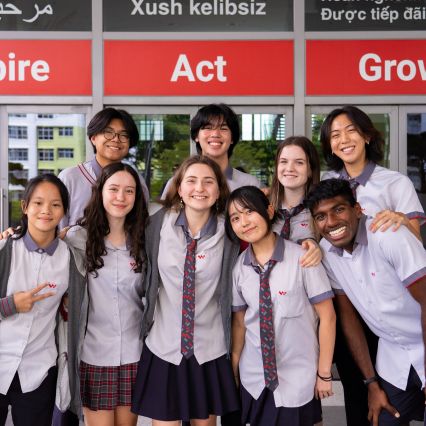 Group of students smiling together outside the multilingual welcome doors