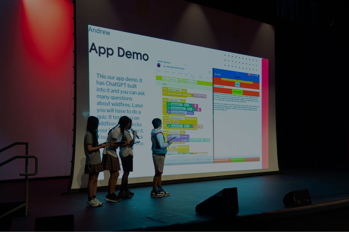 Students presenting an app demo on a large screen on stage
