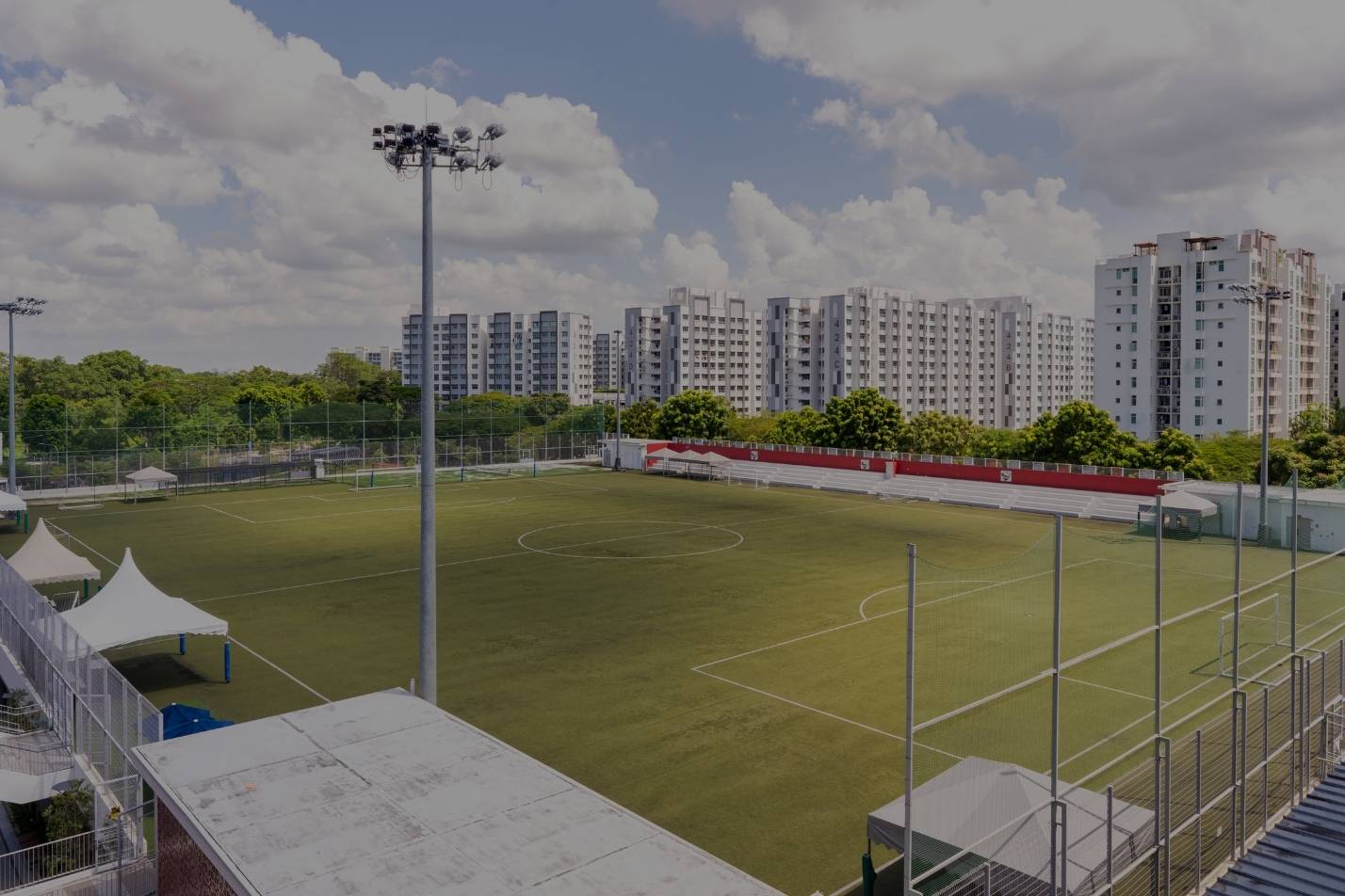 Outdoor football pitch with floodlights and a spectator stand
