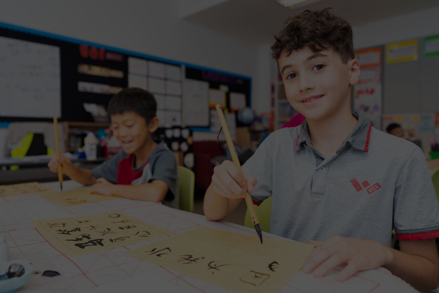A student practising Chinese calligraphy with a brush in class