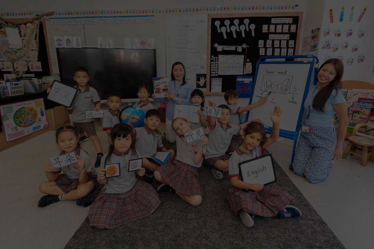 Class of young students and teachers holding word cards in a classroom