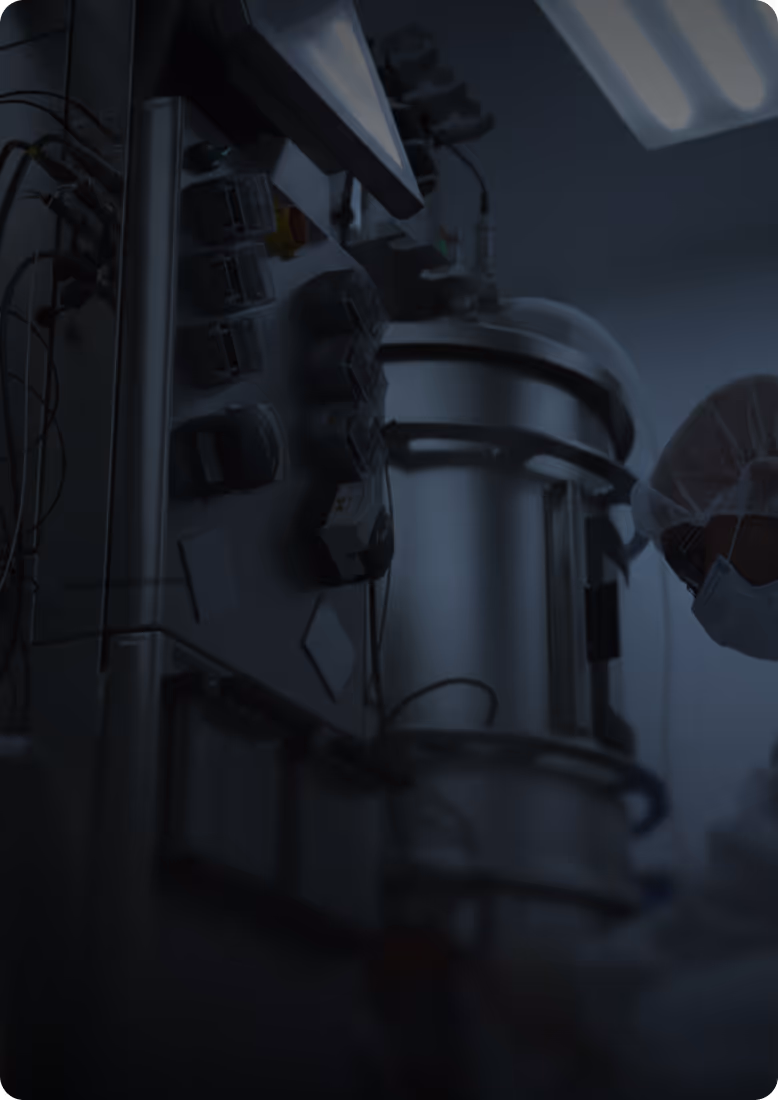 Scientist in protective clothing and mask working with industrial lab equipment in a laboratory.