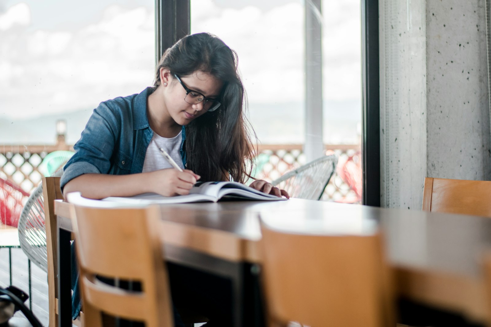 Studentin lernt mit Buechern und Notizen am Schreibtisch