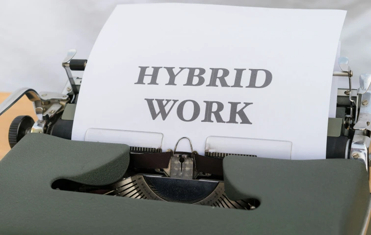 Eine Schreibmaschine, aus der ein Blatt mit der Schrift "Hybrid Work" liegt.