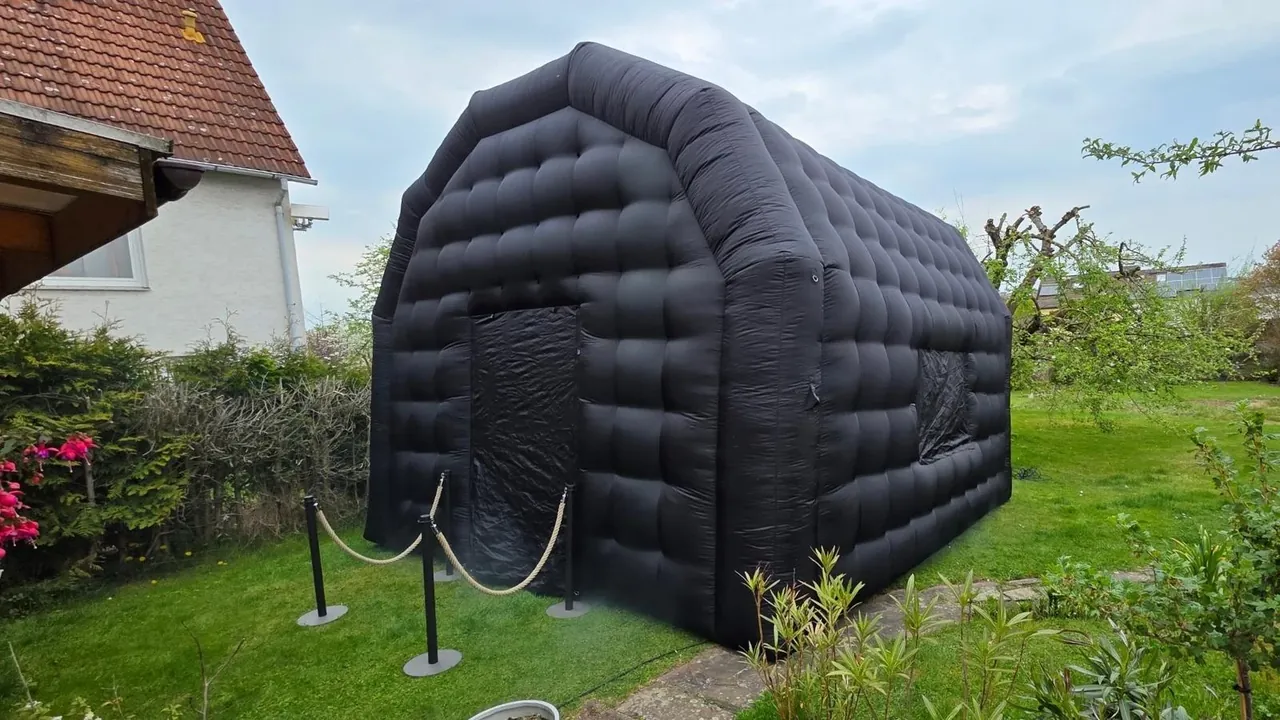 Schwarzes aufblasbares Partyzelt mit Absperrkordel in einem Garten bei Tageslicht