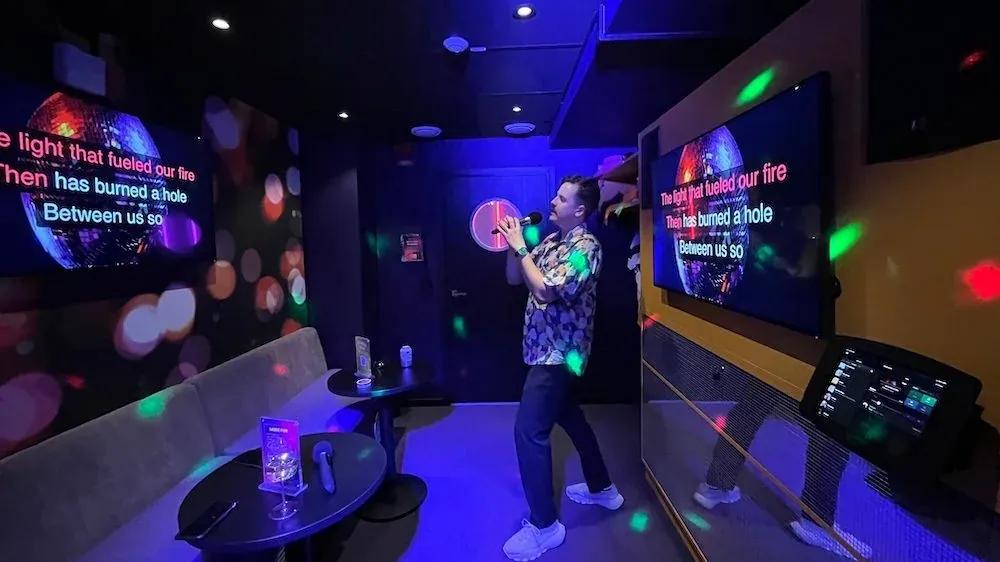 Karaoke mit Funkmikrofon, der Songtext läuft groß auf zwei Bildschirmen