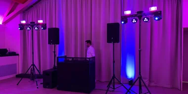 DJ-Pult mit Lautsprechern auf Stativen und Lichtern in einem Saal