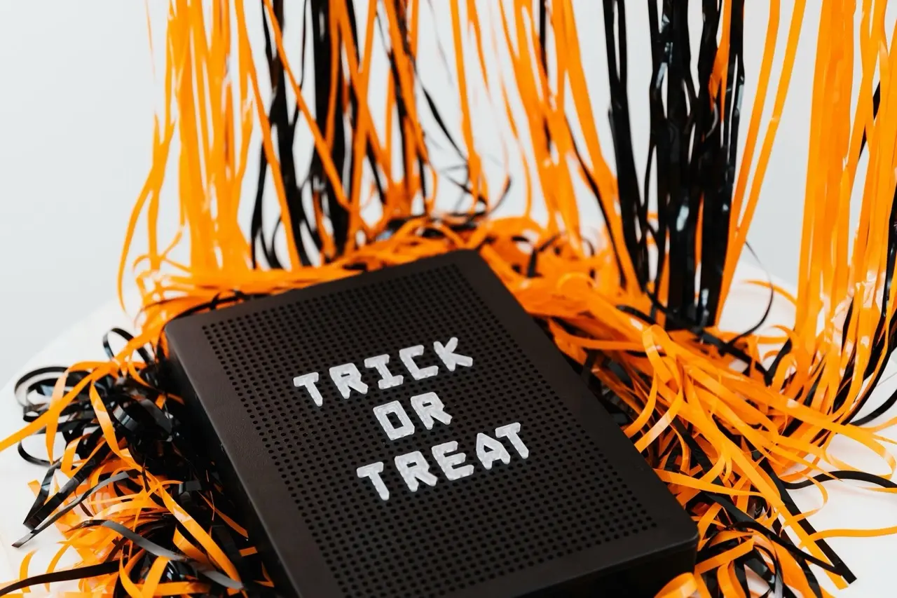 Farbenfrohe Halloween-Dekoration: Das klassische Farbschema in Orange und Schwarz wird durch Papierschlangen und ein Schild mit der Aufschrift „Trick or Treat“ spielerisch für Kinder in Szene gesetzt.