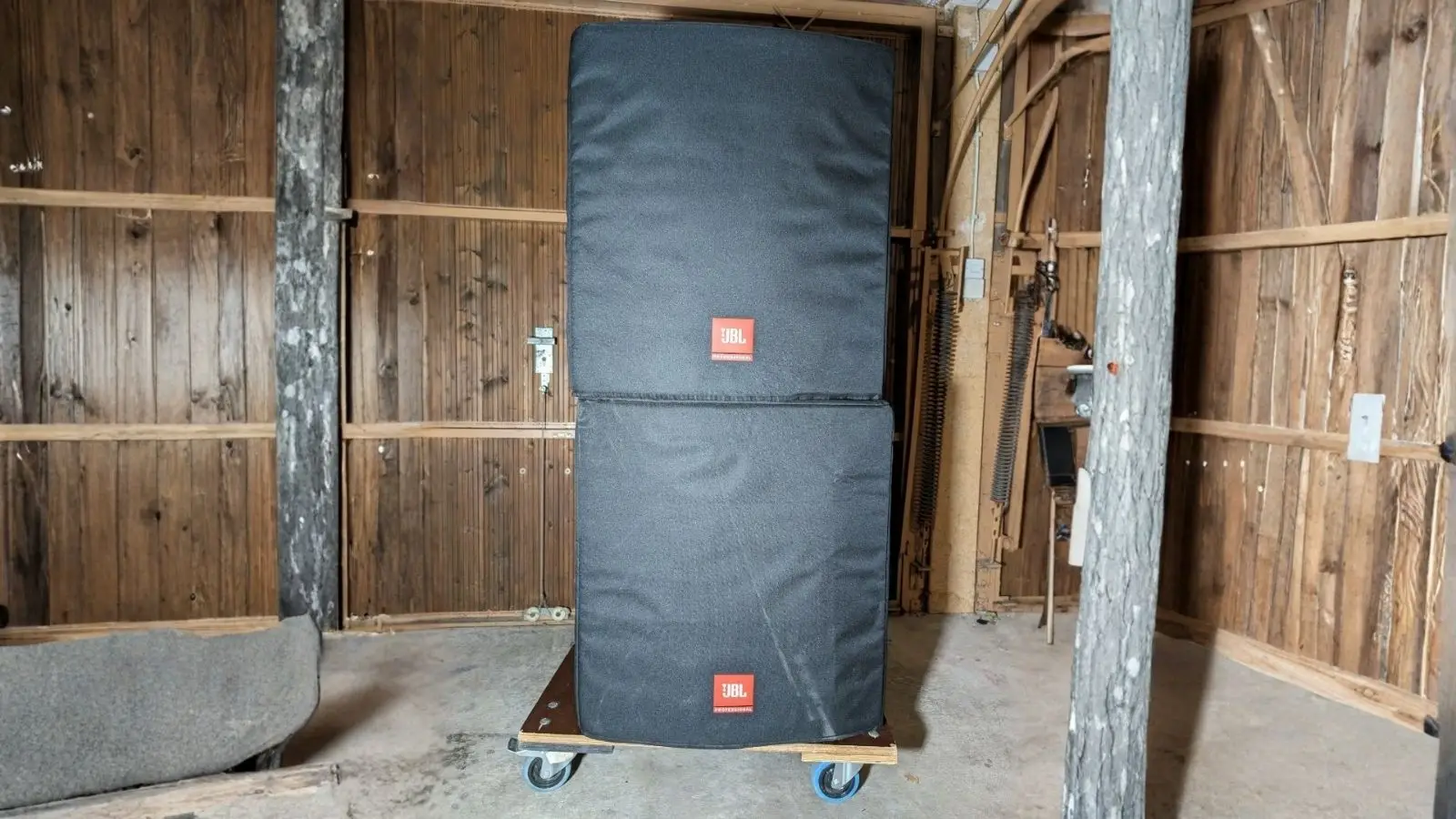 JBL EON PA-Anlage in Schutzhüllen gestapelt auf einem Transportroller in einer Halle.