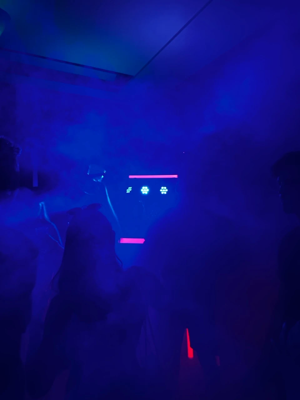 Partygäste im blauen Nebel vor LED-Strahlern und einer Lichtleiste zu Veranstaltungstechnik mieten in Lustenau.