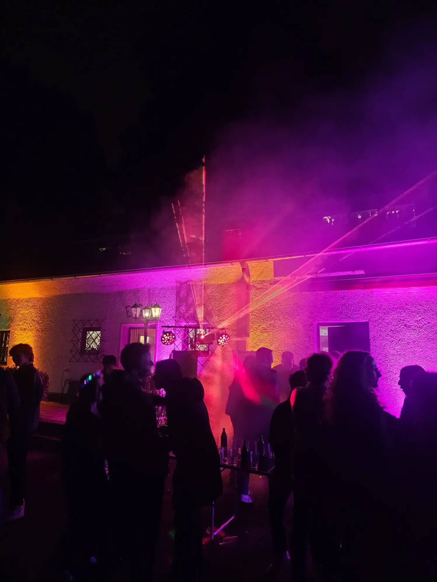 Abendparty mit pinker Fassadenbeleuchtung und feiernden Gästen, Veranstaltungstechnik mieten in Hannover.