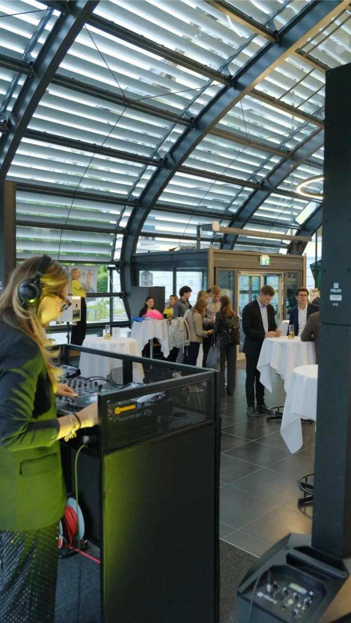 DJane am Pioneer-Pult mit Säulenlautsprecher bei einem Empfang unter Glasdach als Musikanlage mieten in Köln.
