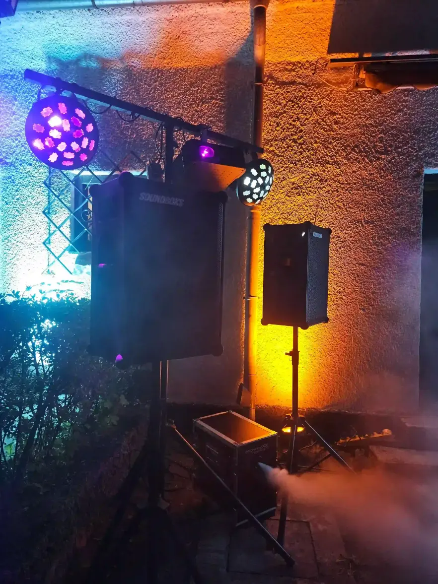 Lautsprecher und bunte Scheinwerfer mit Nebel an einer Hauswand als Veranstaltungstechnik mieten in München.