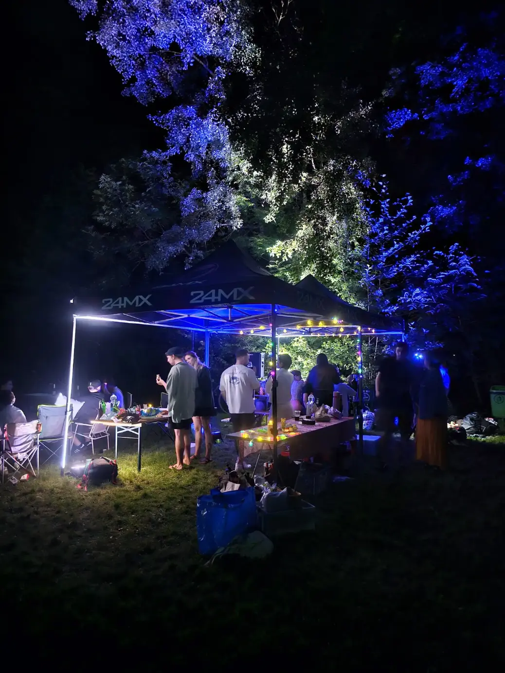 Gartenparty bei Nacht unter einem Pavillon mit blauer Beleuchtung als Veranstaltungstechnik mieten in München.