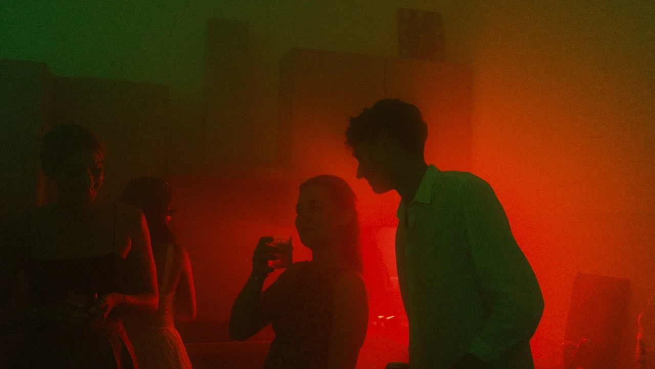 Feiernde Gäste in rotem und grünem Partylicht mit Lautsprechern im Hintergrund, Veranstaltungstechnik mieten in Stuttgart.