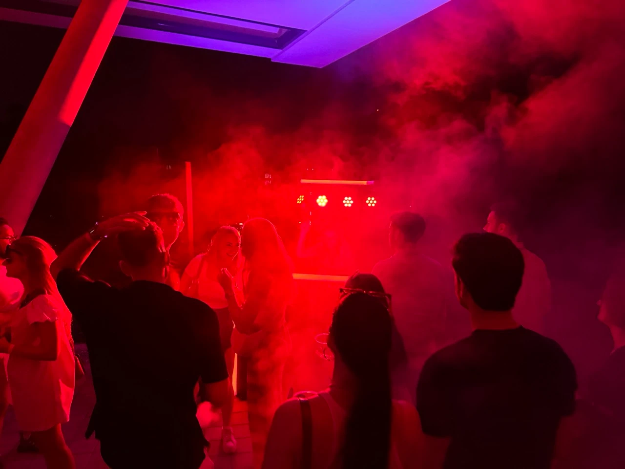 Feiernde Gäste im roten Nebel mit Lichteffekten auf einer Party, Veranstaltungstechnik mieten in Wiesbaden.
