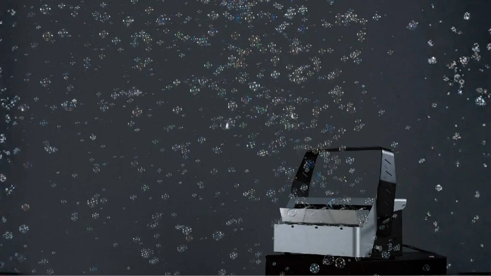 Antari B-200 Bubble Machine DMX im Einsatz, Seifenblasenmaschine verteilt Seifenblasen vor dunklem Hintergrund.