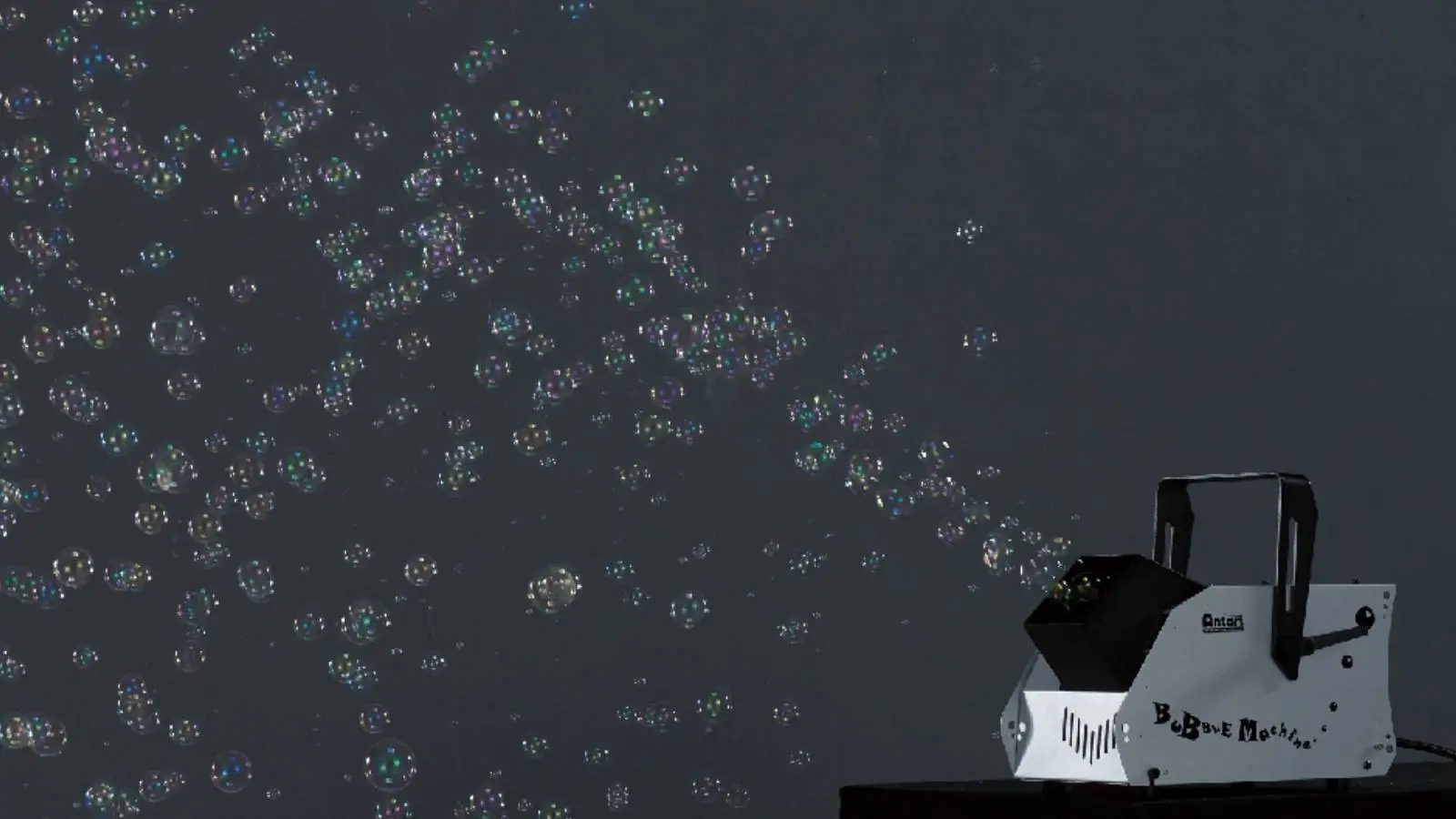 Antari B-100 Bubble Machine im Einsatz, Seifenblasenmaschine erzeugt viele Seifenblasen vor dunklem Hintergrund.