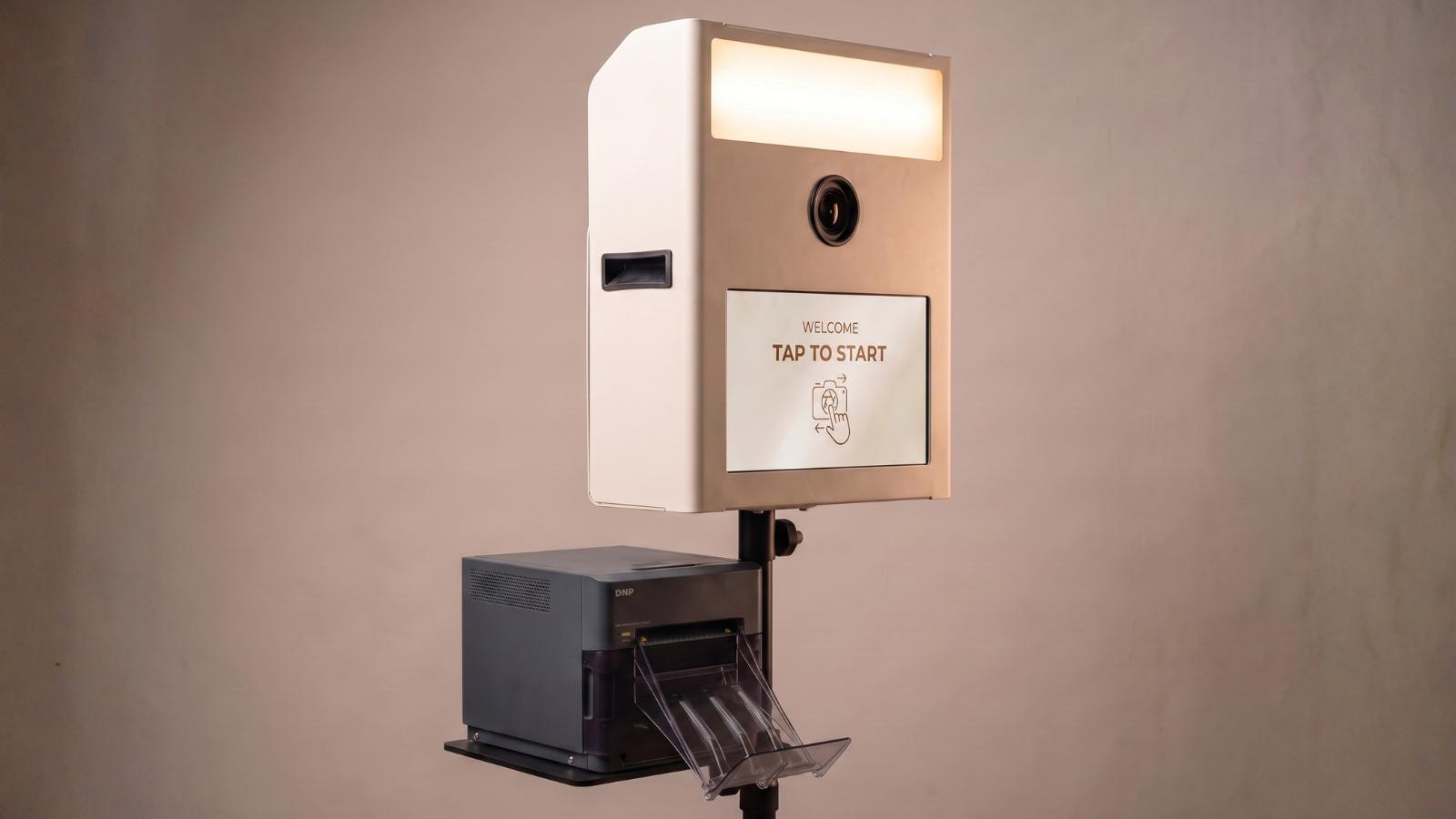 Fotobox Print in Weiß mit Sofortdrucker und Touchscreen mit der Aufschrift Tap to Start.