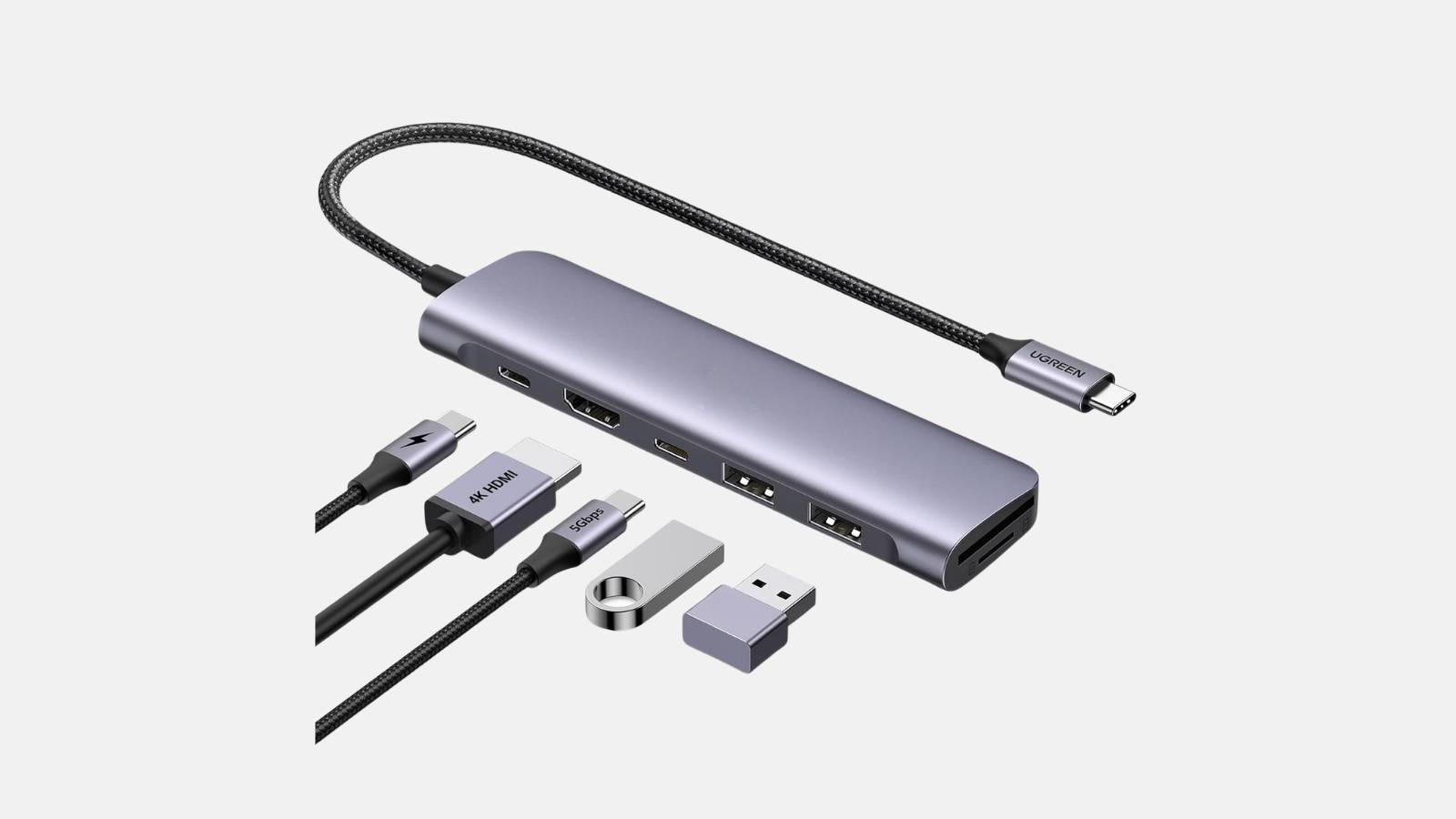 USB-C auf HDMI Adapter in Silbergrau mit mehreren Anschlüssen und Kabeln vor grauem Hintergrund.