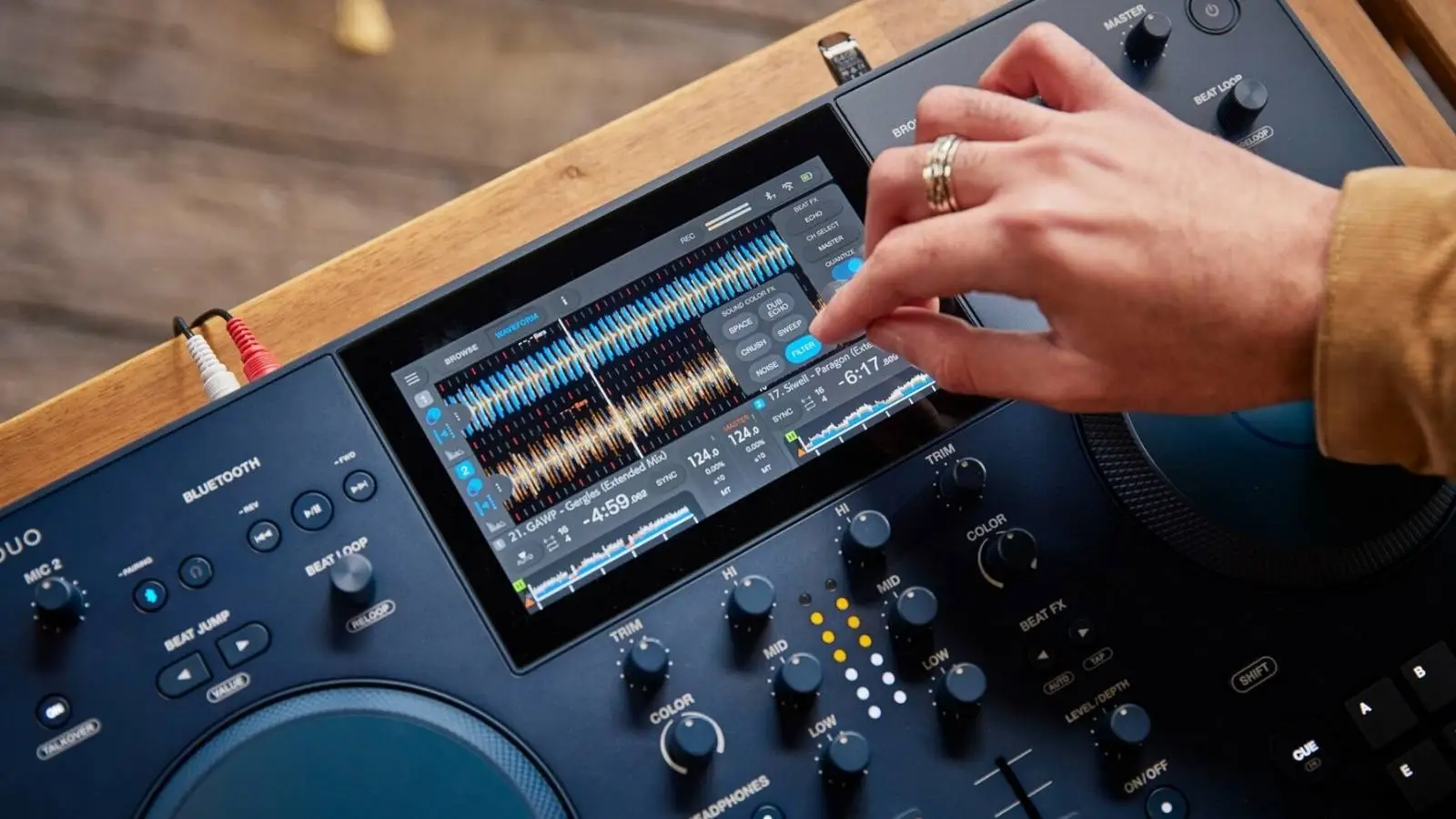 AlphaTheta OMNIS-DUO Standalone DJ-Pult mit Touchscreen und Jog-Wheels in einer Nahaufnahme beim Auflegen.