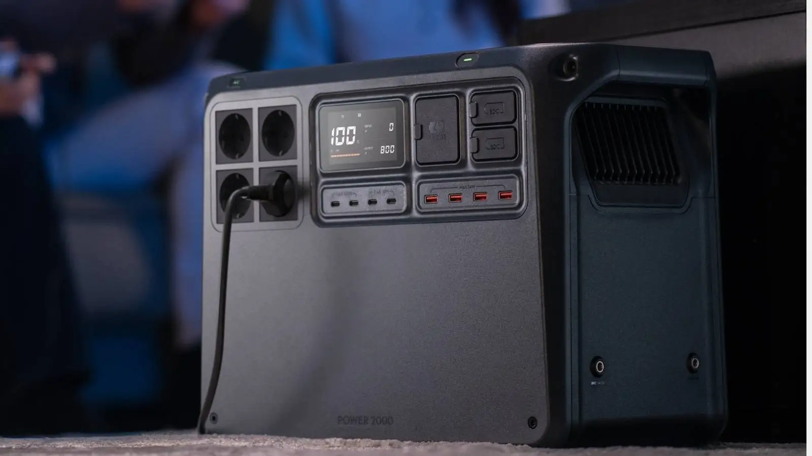 DJI Power 2000 Powerstation mit angestecktem Kabel und beleuchtetem Display im Innenraum-Einsatz.