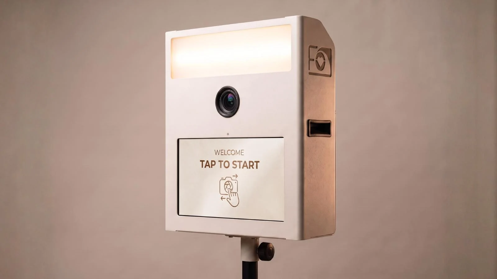 Fotobox Mini in Weiß mit beleuchtetem Ringlicht, Kameralinse und Touchscreen mit Tap-to-Start-Anzeige.
