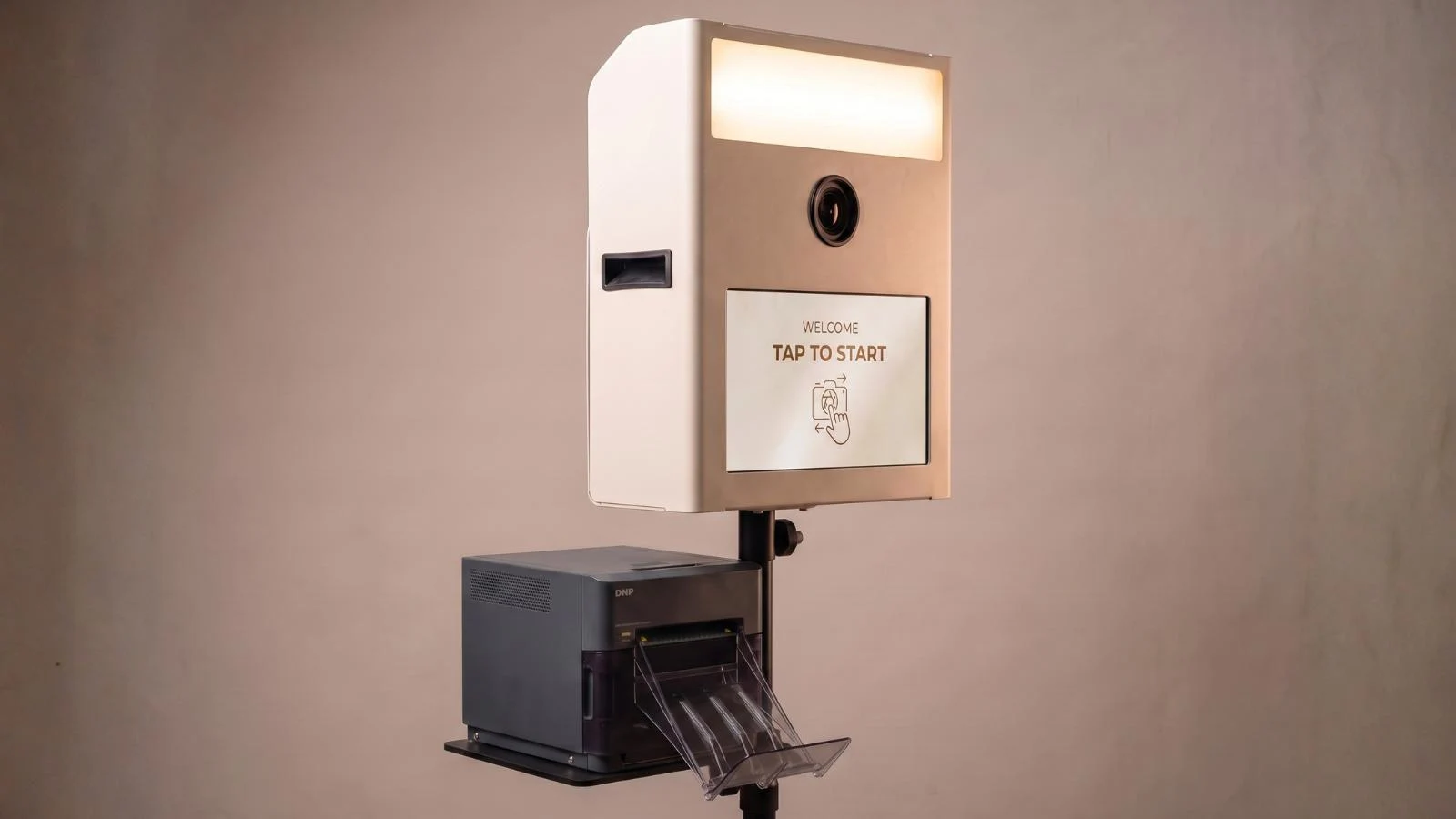 Fotobox Print in Beige mit beleuchtetem Fotobereich, Touchscreen und Sofortdrucker unter dem Gehäuse.