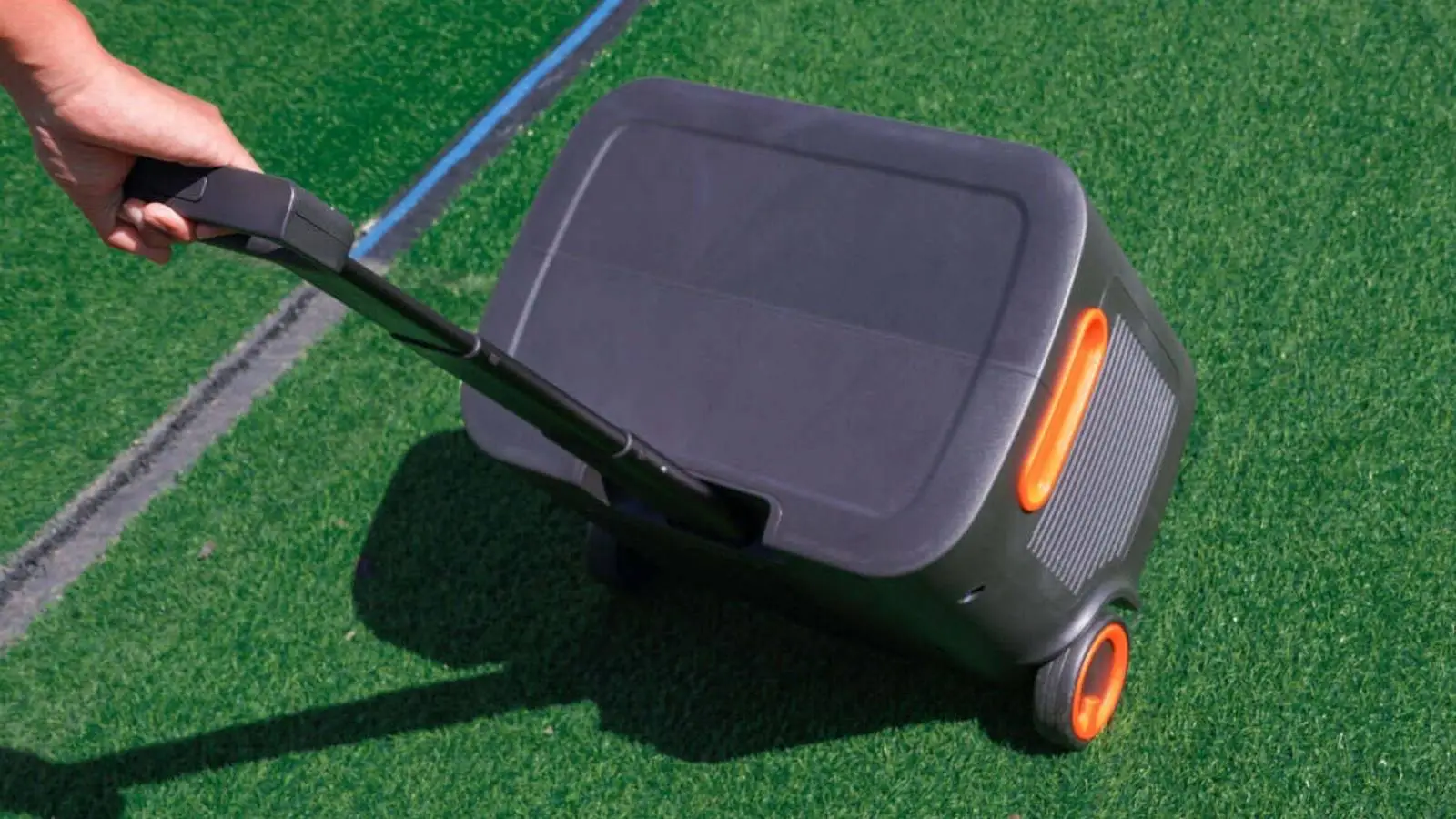 Jackery Explorer 2000 Plus Powerstation mit Teleskopgriff und Rollen wird über einen Rasenplatz gezogen.