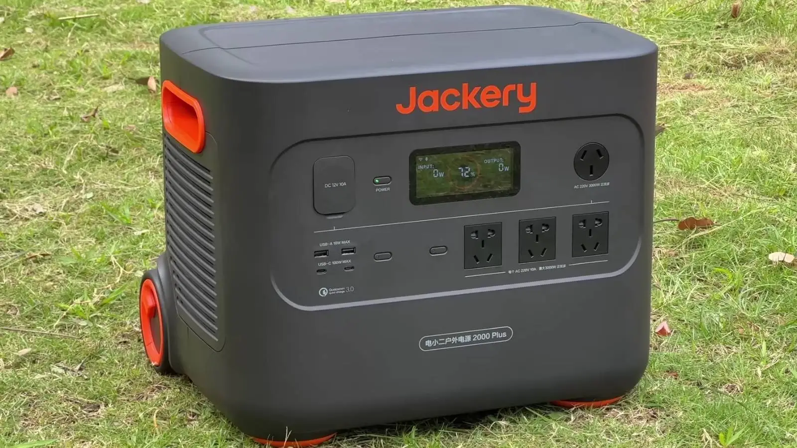 Jackery Explorer 2000 Plus Powerstation mit Display und Steckdosen auf einer Wiese im Freien.