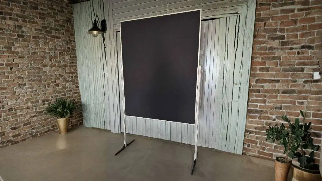 Moderations-Paket mit dunkler Pinnwand auf Standfüßen in einem Raum mit Backsteinwand.