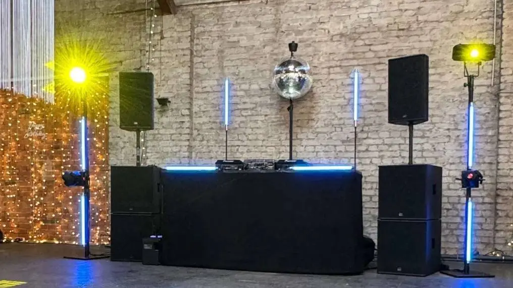 Seeburg Konzert PA Stack im Einsatz mit schwarzen Lautsprechern auf Stativen, DJ-Pult und Discokugel.