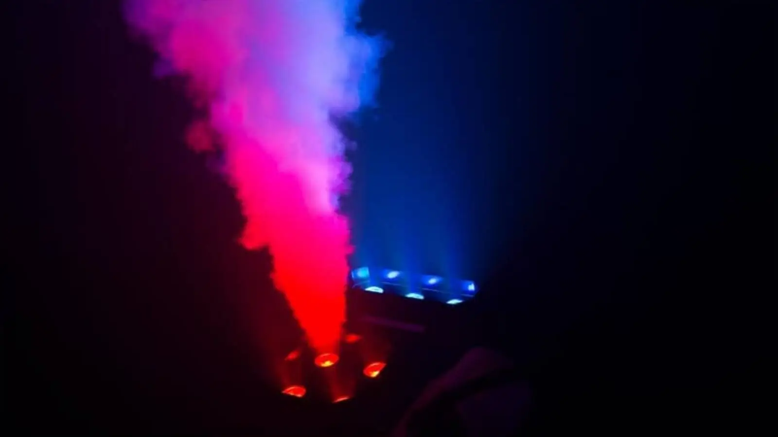 Cameo Geyser P7 Vertikalnebelmaschine mit rot und blau beleuchtetem Nebelstrahl im dunklen Raum.