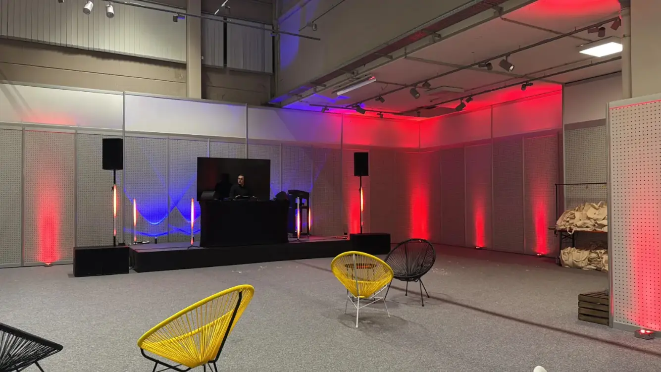 DJ-Pult mit zwei Lautsprechern und roter und blauer Beleuchtung in einer Halle, Musikanlage für Weihnachtsfeier mieten.