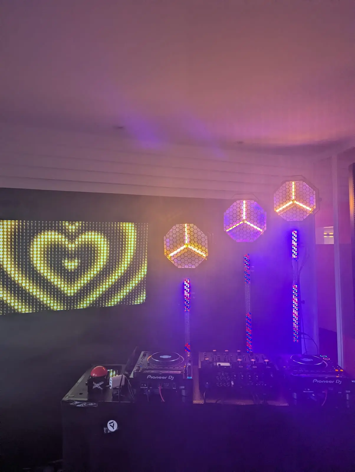 DJ-Pult von Pioneer mit LED-Herzanzeige und Lichteffekten in violettem Licht, Musikanlage für Junggesellenabschied mieten.
