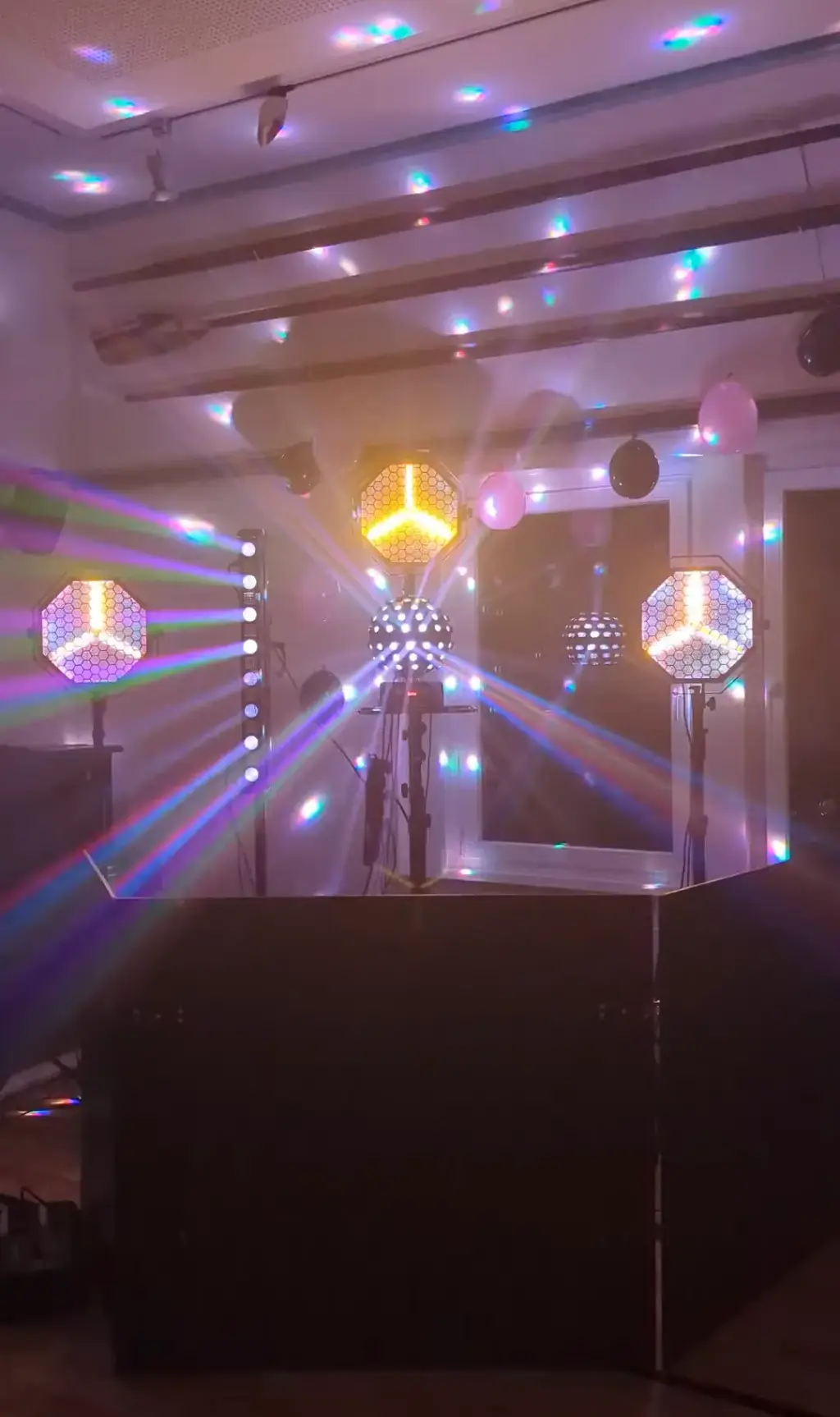 DJ-Pult mit leuchtenden Lichteffekten und Spiegelkugeln im Raum als Veranstaltungstechnik für Silvester mieten.
