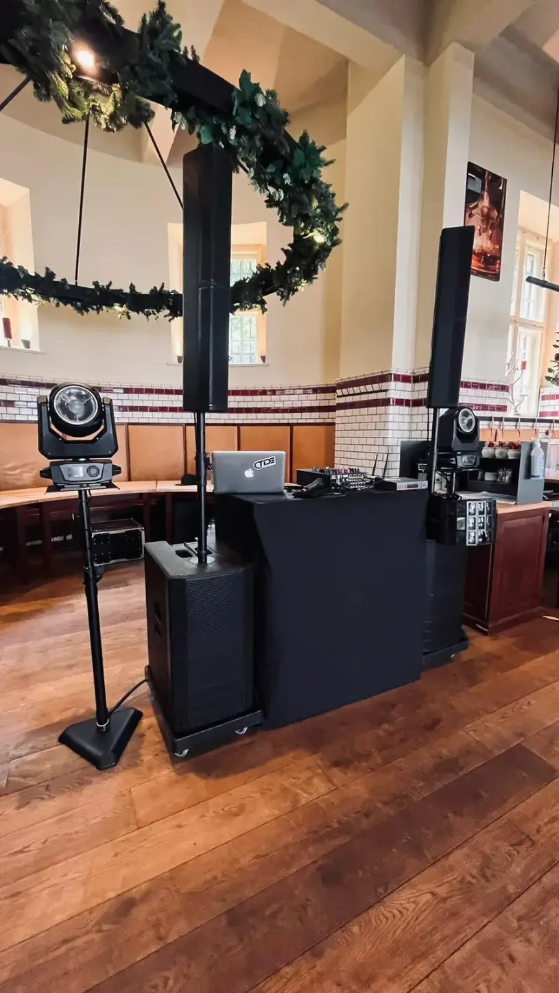 DJ-Setup mit Säulenlautsprechern, Subwoofer und Moving-Head vor einer weihnachtlichen Girlande, PA-Anlage für Weihnachtsfeier mieten.