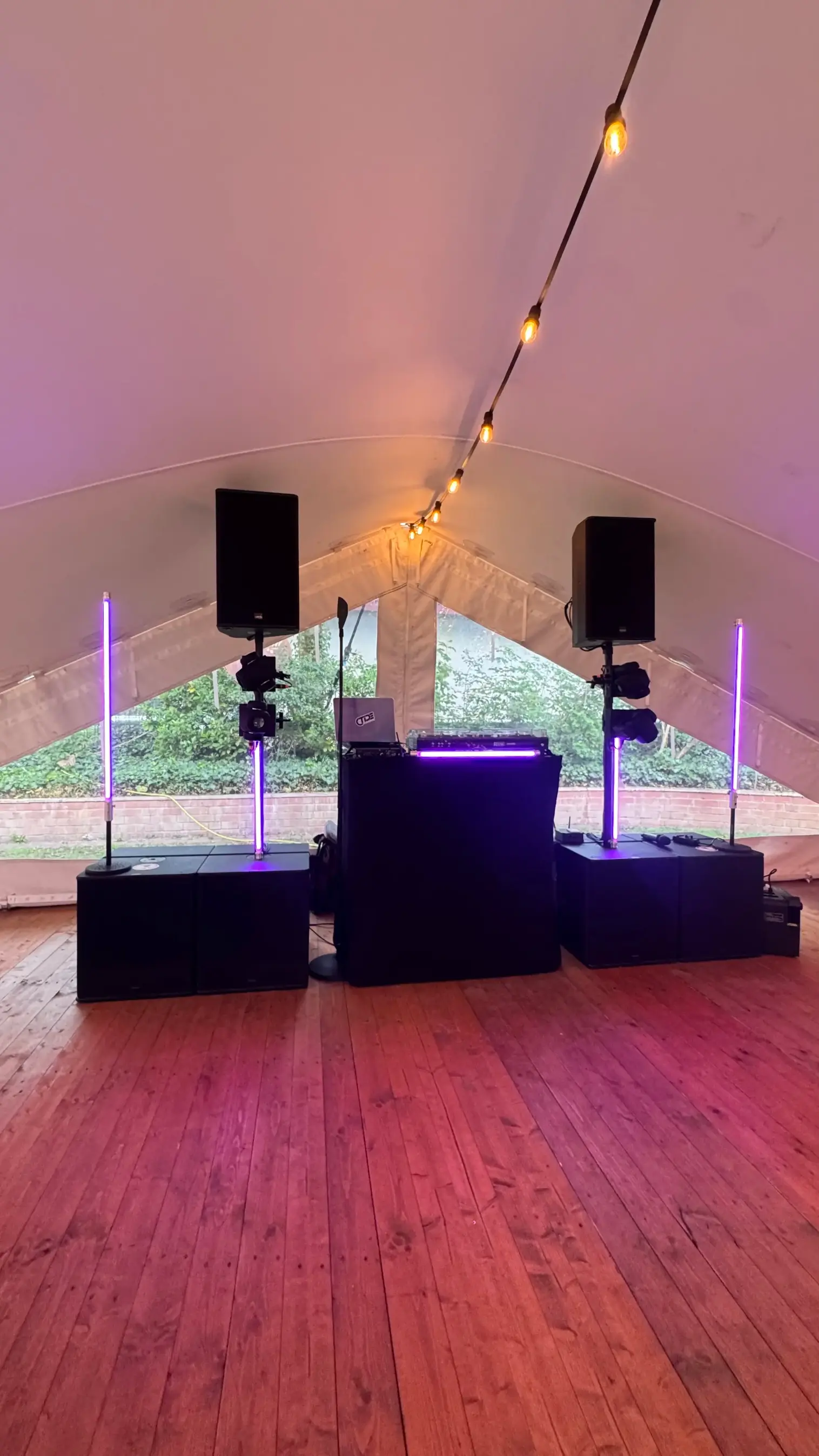 DJ-Setup im Partyzelt mit zwei Lautsprechern auf Stativen und warmweißer Beleuchtung als Musikanlage für Public Viewing mieten.